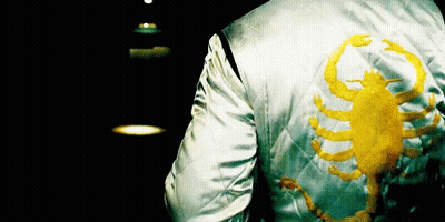 A Person Wearing A White Jacket With A Yellow Scorpion On It GIF