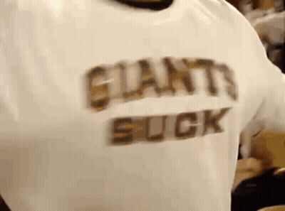 A Person Wearing A White Shirt That Says Giants Suck On It . GIF