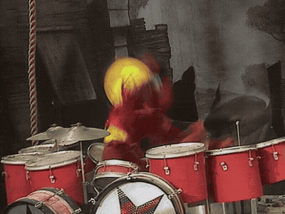 A Person Wearing A Yellow Hat Is Playing A Drum Set GIF