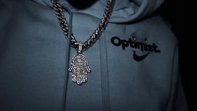 A Person Wearing An Optimistic Hoodie With A Hamsa Pendant GIF