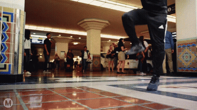 A Person Wearing Black Adidas Pants Is Dancing In A Crowded Room GIF