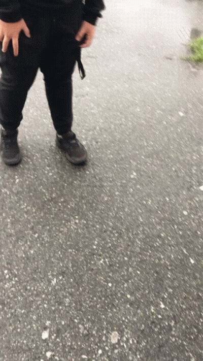 A Person Wearing Black Pants And Black Shoes Is Standing On A Concrete Surface GIF
