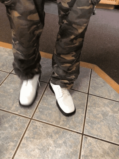 A Person Wearing Camo Pants And White Shoes Stands On A Tiled Floor GIF