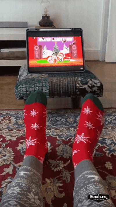 A Person Wearing Christmas Socks Is Sitting In Front Of A Computer GIF