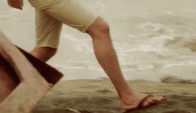 A Person Wearing Flip Flops Is Walking On A Sandy Beach GIF