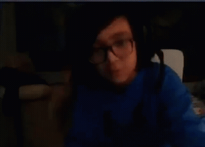 A Person Wearing Glasses And A Blue Shirt Is Making A Funny Face . GIF