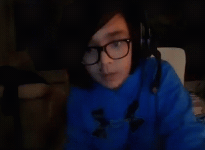 A Person Wearing Glasses And A Blue Sweater Is Sitting In A Chair . GIF