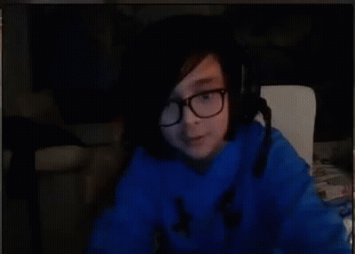A Person Wearing Glasses And A Blue Sweater Is Sitting In Front Of A Computer Screen . GIF