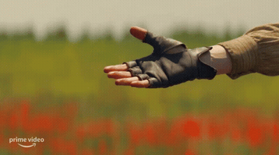 A Person Wearing Gloves Reaches Out To Another Person 'S Hand With A Prime Video Logo In The Background GIF