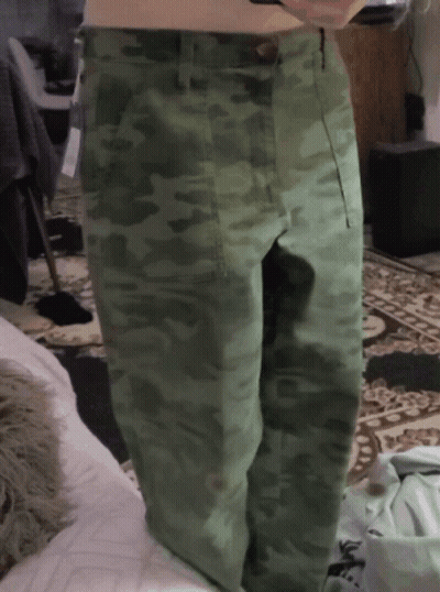 A Person Wearing Green Camo Pants Is Standing On A Rug GIF