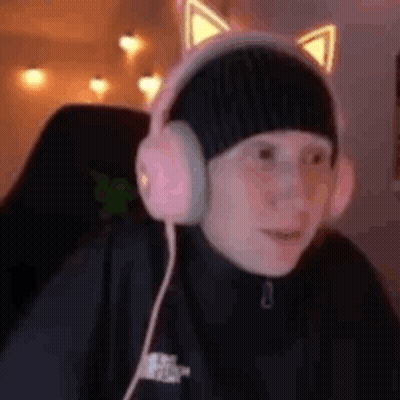 A Person Wearing Headphones And A Hat With Cat Ears Is Sitting In A Chair . GIF