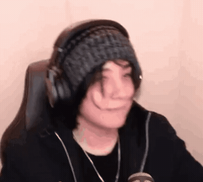 A Person Wearing Headphones And A Knitted Hat Is Sitting In A Chair . GIF