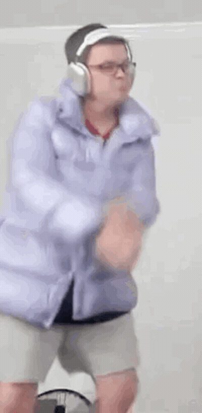 A Person Wearing Headphones And A Purple Jacket Is Dancing . GIF