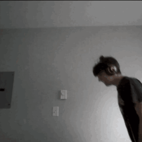 A Person Wearing Headphones Is Standing In A Room . GIF