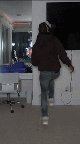 A Person Wearing Headphones Is Standing In Front Of A Television GIF