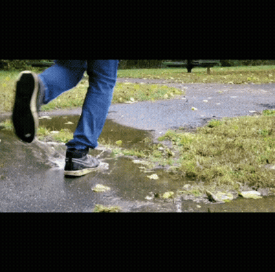 A Person Wearing Nike Shoes Runs Through A Puddle Of Water GIF