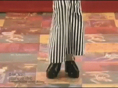 A Person Wearing Striped Pants And Black Shoes Is Standing On A Checkered Floor .. GIF