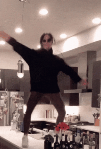 A Person Wearing Sunglasses And A Black Sweater Is Jumping In The Air GIF