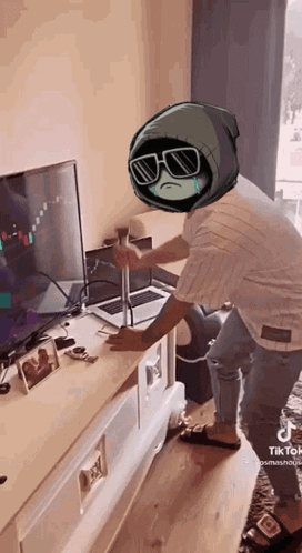 A Person With A Cartoon Character On Their Head Is Standing In Front Of A Laptop And A Television . GIF