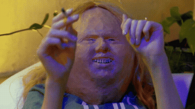 A Person With A Mask On Their Face Is Holding A Cigarette GIF