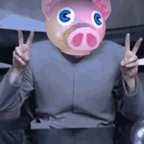 A Person With A Pig Mask On Their Head Giving A Peace Sign GIF