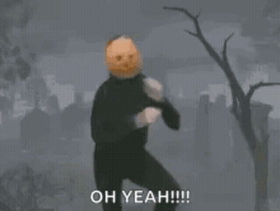 A Person With A Pumpkin On Their Head Is Standing On One Leg In A Cemetery . GIF