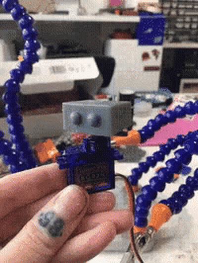 A Person With A Tattoo On Their Finger Is Holding A Robot GIF