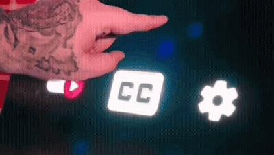 A Person With A Tattoo On Their Wrist Is Pointing At A Screen With A Cc Icon And A Gear Icon . GIF