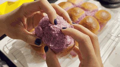 A Person With Blue Nails Is Holding A Purple Donut GIF