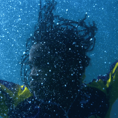 A Person With Dreadlocks Is Swimming Underwater GIF