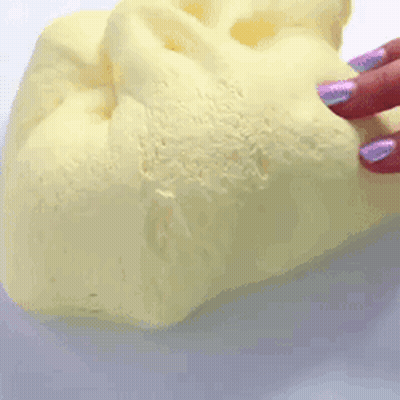 A Person With Purple Nails Is Holding A Piece Of Yellow Foam . GIF