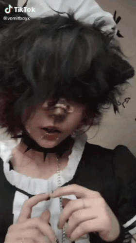 A Person With Short Black Hair And A Choker Around Their Neck Is Wearing A Maid Costume . GIF