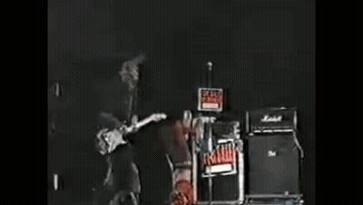 A Person With Spikes On Their Head Is Standing In A Dark Room GIF