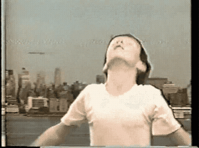 A Person With Their Arms Outstretched Looking Up At The Sky GIF