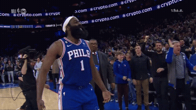 A Philadelphia Basketball Player Stands In Front Of A Crowd With His Fist In The Air GIF