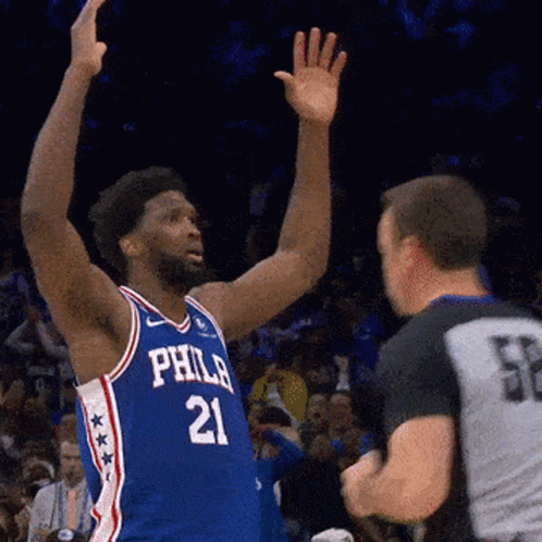 A Philadelphia Basketball Player Wearing Number 21 Reaches Up Towards A Referee GIF