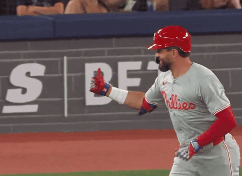 A Phillies Baseball Player Is Giving A High Five In Front Of A Wall That Says Sbf GIF