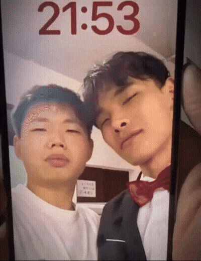 A Phone Screen Shows A Picture Of Two Men And The Time Is 2153 GIF