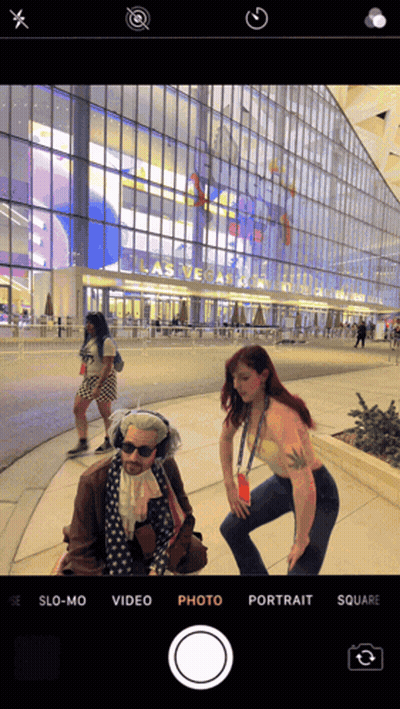 A Phone Screen Shows A Woman Taking A Picture Of A Man In Front Of A Building That Says Las Vegas GIF