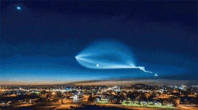 A Picture Of A City At Night With A Blue Sky And A Star In The Background GIF