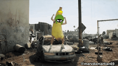 A Picture Of A Man Dressed As Marvin The Martian Standing On A Car GIF