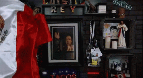 A Picture Of A Man Hanging On A Wall With A Sign That Says Luis Ave GIF