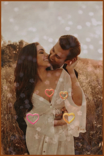 A Picture Of A Man Kissing A Woman With Hearts Around Them And The Name Vica On The Bottom Right GIF