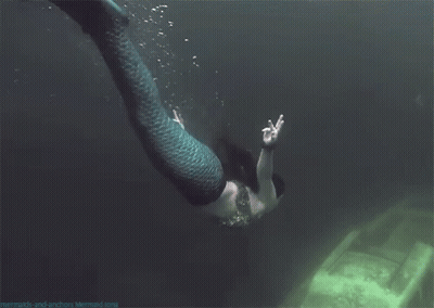 A Picture Of A Mermaid Swimming Next To A Boat With The Website Mermaids-And-Anchors Mermaid.org GIF