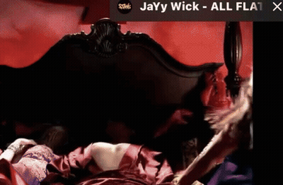 A Picture Of A Woman Laying On A Bed With The Words Jayy Wick All Flat X On The Bottom GIF