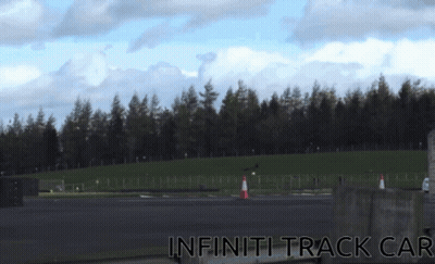 A Picture Of An Infiniti Track Car With A Forest In The Background GIF