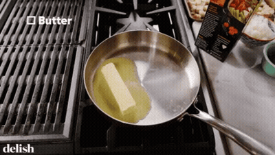 A Piece Of Butter Is In A Frying Pan On A Stove Top GIF
