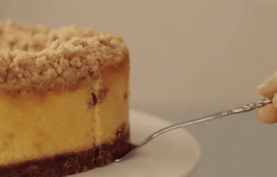 A Piece Of Cheesecake With Raisins And Crumb Topping On A White Plate GIF