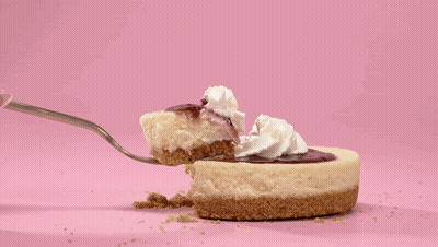A Piece Of Cheesecake With Whipped Cream On Top Is Being Eaten With A Fork GIF