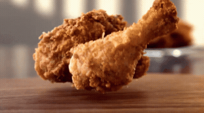 A Piece Of Fried Chicken Is On A Wooden Table GIF